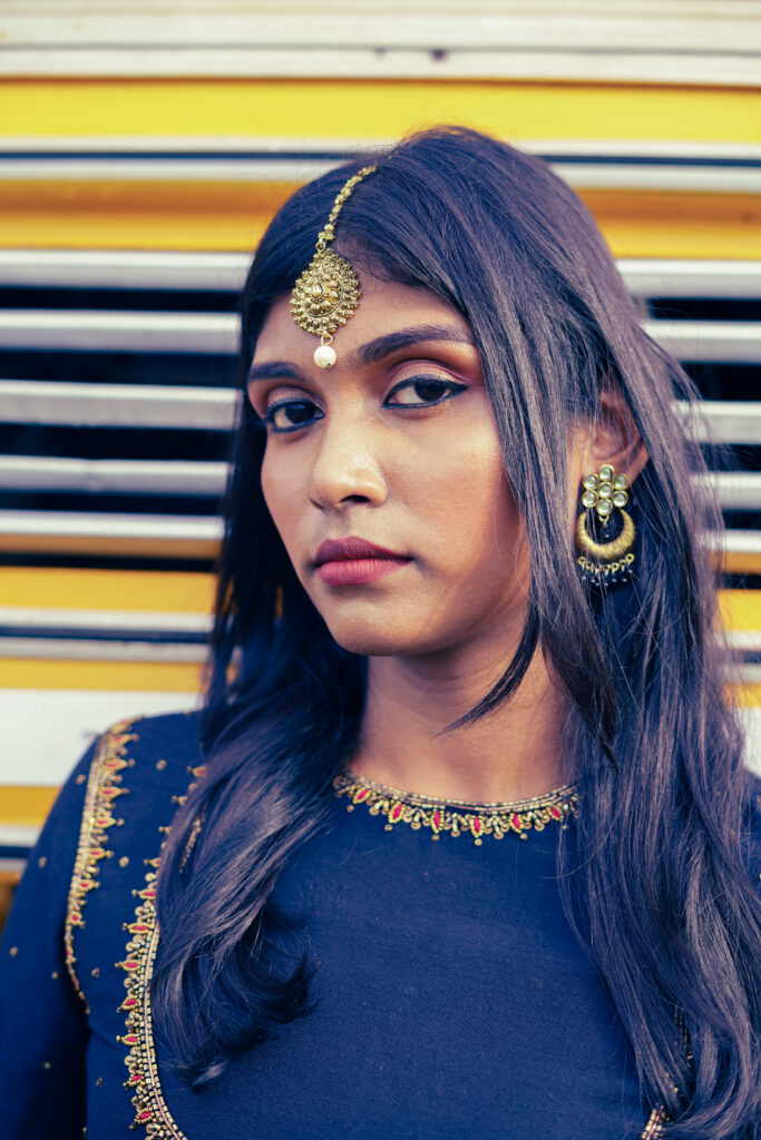 Woman in a navy embroidered blouse, maang tikka and gold lehenga