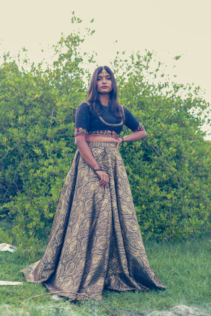 Woman in a navy embroidered blouse, maang tikka and gold lehenga