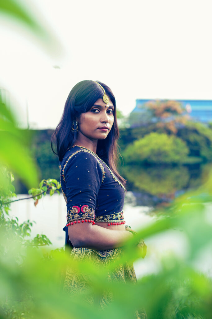 Woman in a navy embroidered blouse, maang tikka and gold lehenga