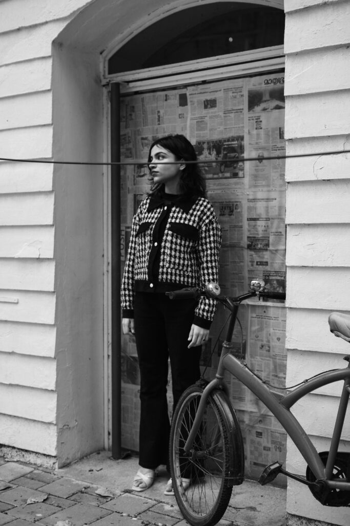 Black and white photo of a woman beside a bicycle in an old doorway