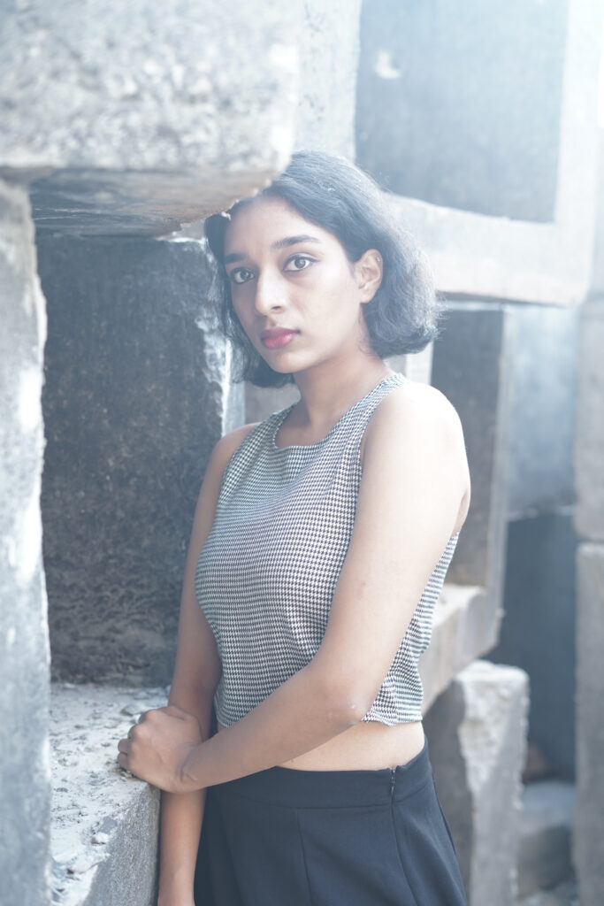 Woman in a striped knit top and black skirt among concrete blocks