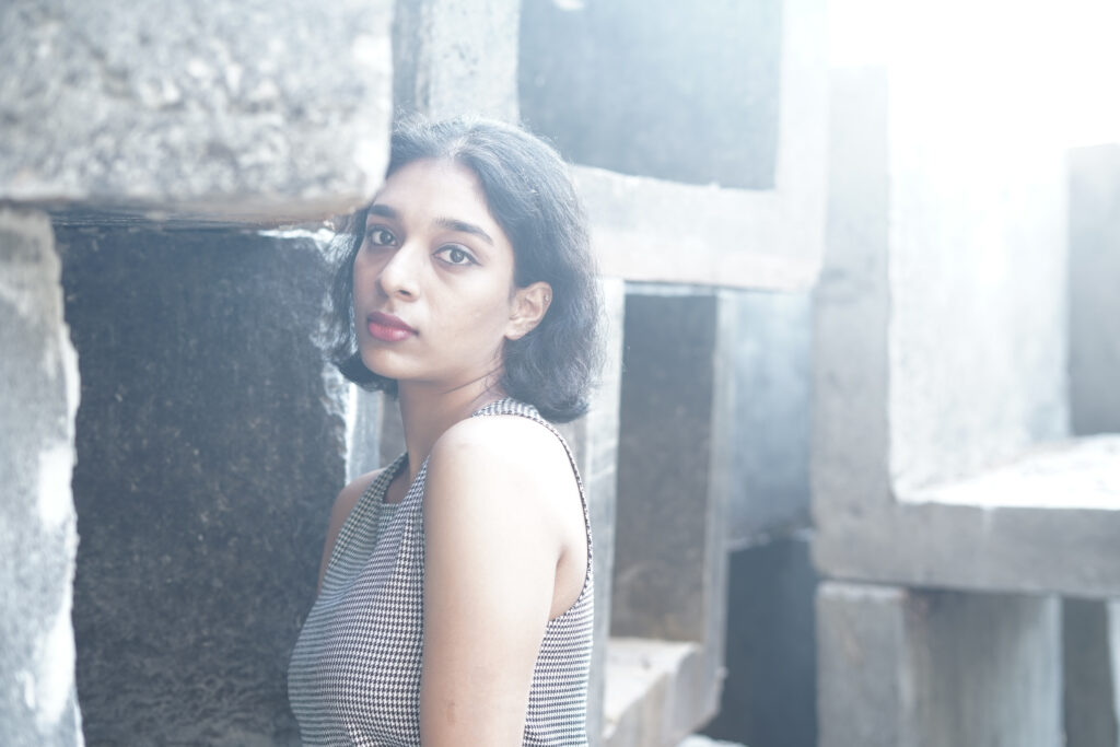 Woman in a striped knit top and black skirt among concrete blocks