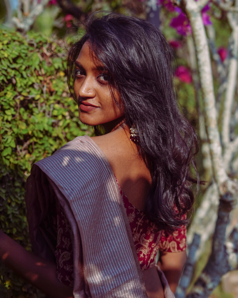 Woman in a grey saree and red printed blouse with jhumka earrings