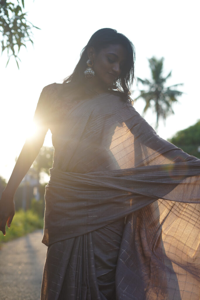 Woman in a grey saree and red printed blouse with jhumka earrings