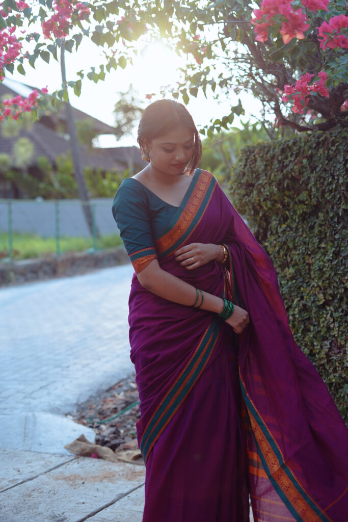 Woman in a magenta silk saree with a green blouse among plants and flowers
