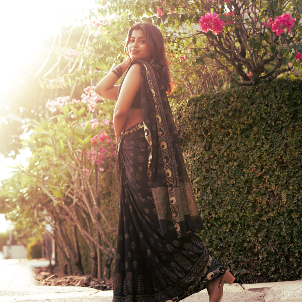 Full-length portrait beside a hedge of pink bougainvillea in low sun