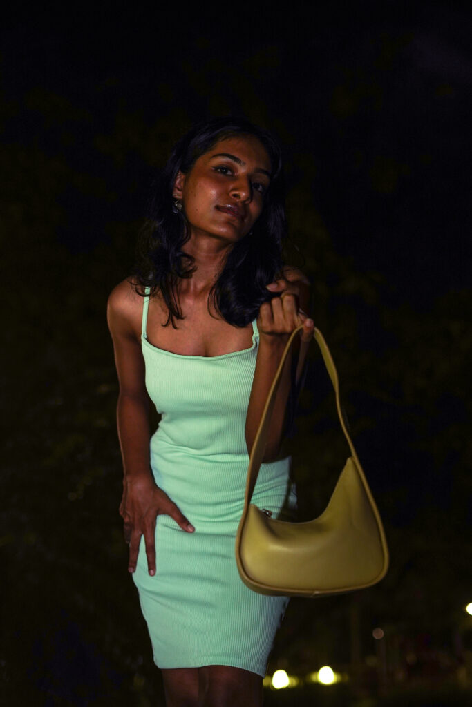 Night portrait of a woman in a mint dress holding a mustard handbag