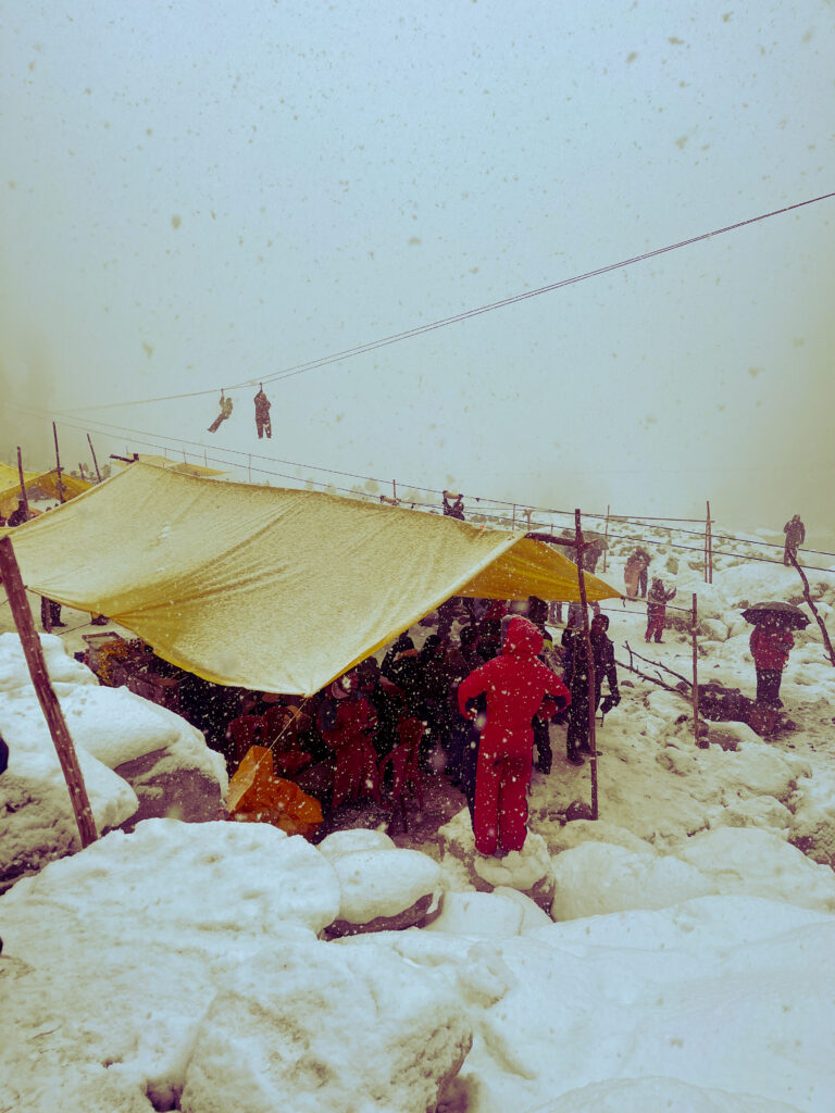 Tourists in bright jackets beside a tarpaulin stall on snow
