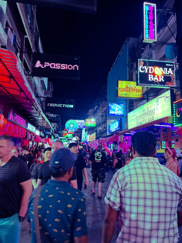 Crowded nightlife street lined with neon bar signs