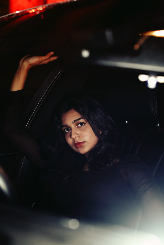 Woman in a dark car interior lit by passing city lights at night