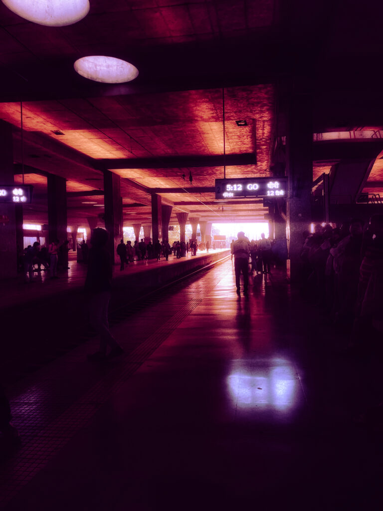 Railway platform glowing in magenta light with passengers in silhouette