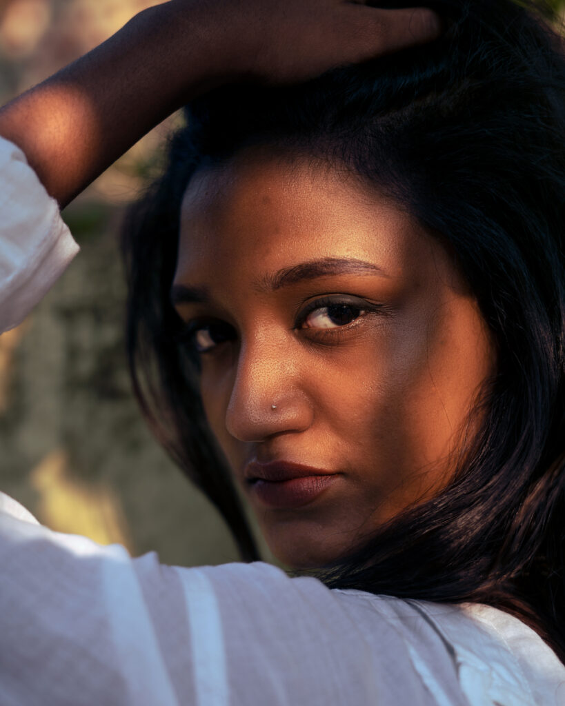 Close portrait of a woman with her hand in her hair in warm light