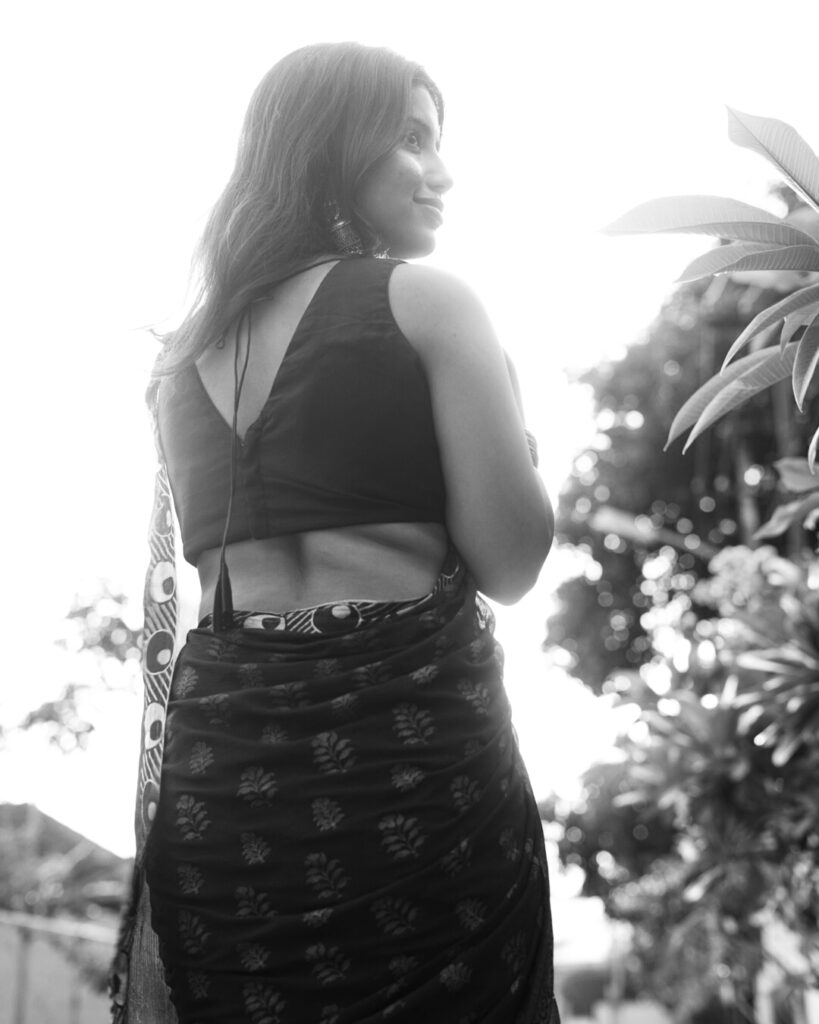 Black and white portrait of a woman in a saree with sun flare on a village road